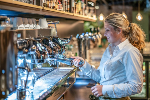 Barista bereitet Kaffee an einer Espressomaschine in einem kleinen, stilvollen Haus zu.