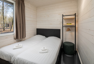 Bedroom in tiny house Holiday Park «Schaijk 2» Netherlands with twin beds and a window to the woods.