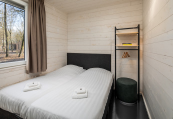 Chambre dans un tiny house Holiday Park «Schaijk 2» aux Pays-Bas, avec deux lits simples et fenêtre.
