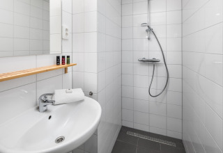 Bagno moderno in una tiny house a Holiday Park Schaijk 2, Paesi Bassi, con doccia, lavabo e mensola.