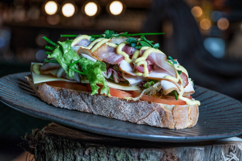 Savoureux sandwich ouvert avec jambon, fromage, laitue et moutarde sur une assiette dans une tiny house.