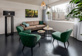 Stilfuld stue i Holiday Park Schaijk 2 med grønne stole, stor sofa og stort vindue i Holland.