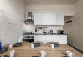 Cucina compatta e zona pranzo con mobili bianchi in una tiny house dell’Holiday Park Schaijk, Paesi Bassi.
