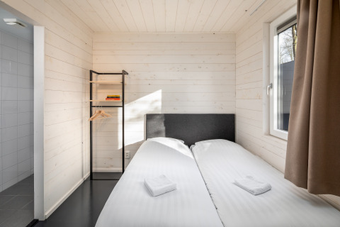 A bright, minimalist bedroom with two single beds in the tiny house Holiday Park Schaijk 2, Netherlands.