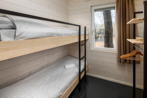 Small room with bunk beds, a window, and open wardrobe in Holiday Park 'Schaijk 2', Netherlands.