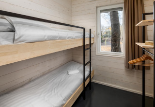 Small room with bunk beds, a window, and open wardrobe in Holiday Park 'Schaijk 2', Netherlands.