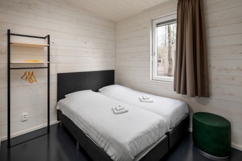 Dormitorio minimalista en Holiday Park «Schaijk 1» en Países Bajos con dos camas individuales y ventana.
