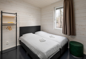 Chambre moderne au Holiday Park «Schaijk 1» aux Pays-Bas avec deux lits jumeaux et une décoration simple.