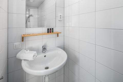 Bagno compatto in Holiday Park Schaijk 1, Paesi Bassi, con lavabo, specchio e mensola in legno.