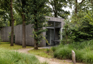 Wood-clad tiny house at Holiday Park Schaijk 1 in the Netherlands, surrounded by trees and greenery.