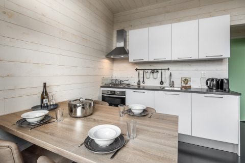 Kompakte moderne Küche mit Esstisch und weißen Schränken in Holiday Park «Schaijk 1», Niederlande.