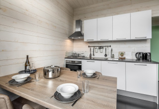 Kompakte moderne Küche mit Esstisch und weißen Schränken in Holiday Park «Schaijk 1», Niederlande.