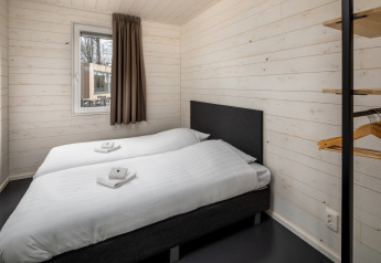 Chambre d'une tiny house Holiday Park «Schaijk 1» aux Pays-Bas, deux lits simples, murs en bois clair.