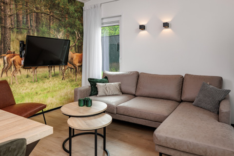 Modernes Wohnzimmer im Tiny House Holiday Park Schaijk 6, Niederlande, mit Hirsch-Wandbild und Sofa.
