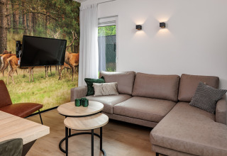 Modernes Wohnzimmer im Tiny House Holiday Park Schaijk 6, Niederlande, mit Hirsch-Wandbild und Sofa.