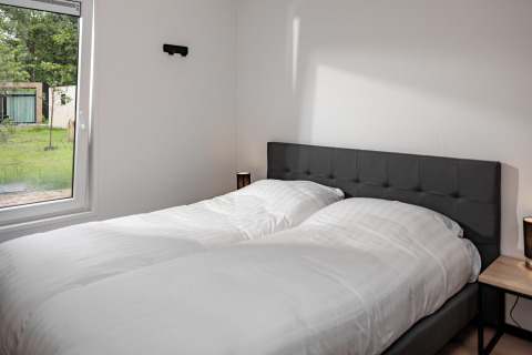 Schlafzimmer in einem Tiny House mit zwei Einzelbetten, großem Fenster und modernem, schlichtem Stil.