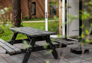Table de pique-nique extérieure devant la porte ouverte d'une tiny house au Holiday Park Schaijk, Pays-Bas.