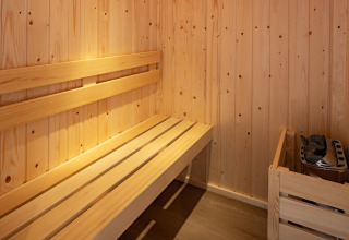 Intérieur d’un petit sauna en bois avec banc et poêle au Holiday Park «Schaijk 6» aux Pays-Bas.