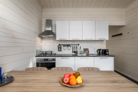 Modern tiny house kitchen at Holiday Park Schaijk 4, Netherlands, with fruit basket on dining table.