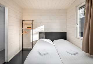Soveværelse i Holiday Park «Schaijk 4» i Holland, med to enkeltsenge, vindue og moderne indretning.