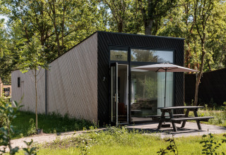 Tiny house moderne au Holiday Park Schaijk 7, Pays-Bas, terrasse avec parasol et environnement verdoyant.