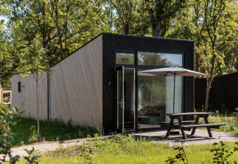 Tiny house moderne au Holiday Park Schaijk 7, Pays-Bas, terrasse avec parasol et environnement verdoyant.