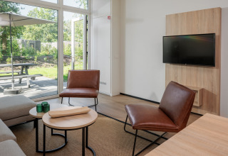 Salon moderne d’une tiny house au Holiday Park Schaijk 7, Pays-Bas, avec fauteuils en cuir et télé.