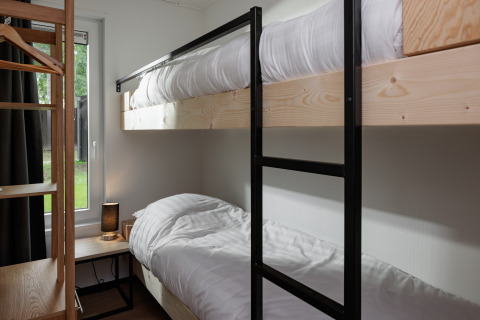 Literas modernas en una pequeña habitación en Holiday Park Schaijk 7, Países Bajos, con detalles de madera.
