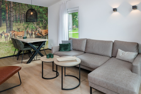 Moderne stue i Holiday Park «Schaijk 5», Holland, med hjørnesofa og naturvægmaleri af kronhjorte.