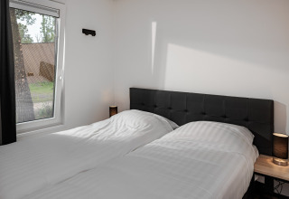 Soveværelse med to enkeltsenge, sorte sengegavle, natborde og store vinduer i Holiday Park Schaijk 5.