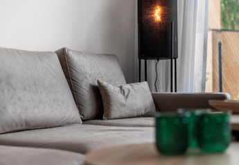 Salon moderne avec canapé gris, verres verts et lampe douce dans un tiny house au Holiday Park Schaijk, NL.