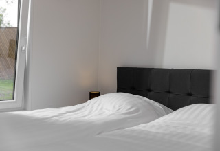 Camera da letto nel tiny house Holiday Park «Schaijk 5» nei Paesi Bassi, con letto e finestra.