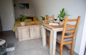 Cozy interior of the 'De Ree en de Specht' pod in the Netherlands featuring wooden furniture and plants.