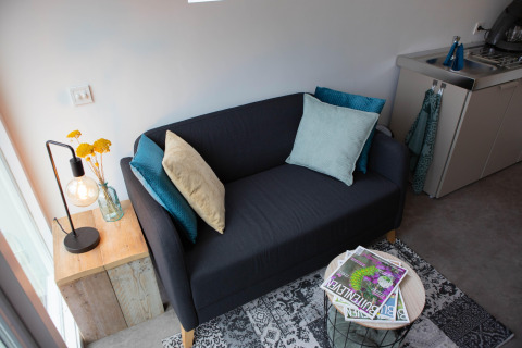 Lille sort sofa med farverige puder i en moderne pod, De Ree en de Specht, Holland, tæt på et tekøkken.