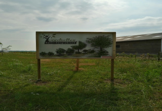 Skilt ved indgangen til fødselsskoven Kattenbergsbroek på en grøn mark nær en lade i Nederlandene.
