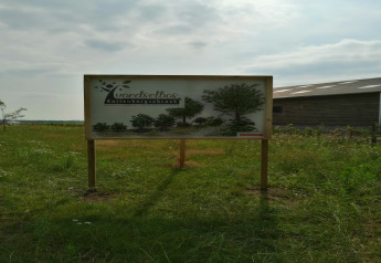 Sign at the entrance of the food forest Kattenbergsbroek on a grassy field near a barn in the Netherlands.