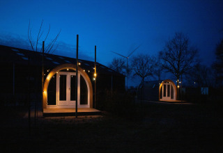 To oplyste pods ved «De Ree en de Specht» i Holland, omgivet af træer og en vindmølle i baggrunden.