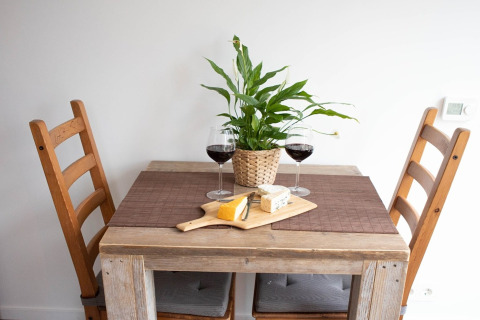 Et lille spisebord med to stole, to glas rødvin, ostebræt og en plante, taget i De Ree en de Specht.