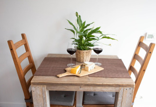 Et lille spisebord med to stole, to glas rødvin, ostebræt og en plante, taget i De Ree en de Specht.