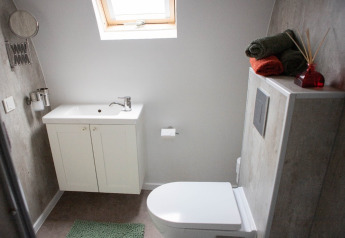 Modern bathroom with white vanity, toilet, decorative towels, and skylight at De Ree en de Specht, Netherlands.