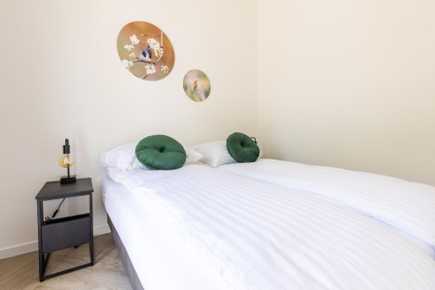 Bright bedroom at Holiday Park 'Molenvelden 8' in the Netherlands with bed, art, and a modern side table.