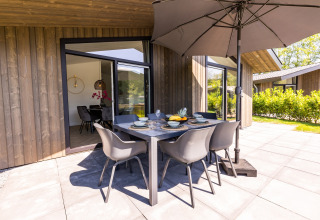 Outdoor dining set with umbrella at Holiday Park Molenvelden 8 chalet, Netherlands, with modern decor.