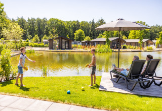 Familie entspannt am Teich mit modernen Chalets im Holiday Park Molenvelden 8, Niederlande, Sommertag.