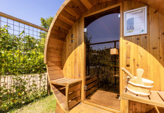 Udendørs træsauna med bænk og spand, solbeskinnet ved Holiday Park Molenvelden 8 i Holland.