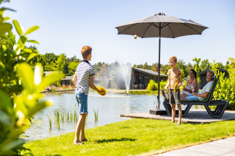 Family enjoying a summer day by the lake at Holiday Park Molenvelden 8, Netherlands, kids playing.