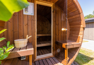 Wooden barrel sauna with glass door and bench at Holiday Park Molenvelden 8 in the Netherlands.