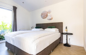 Dormitorio luminoso con dos camas individuales, decoración moderna y ventana grande en Molenvelden 7.