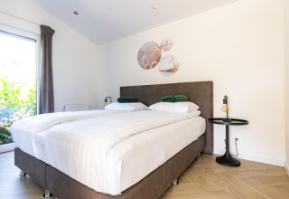 Dormitorio luminoso con dos camas individuales, decoración moderna y ventana grande en Molenvelden 7.