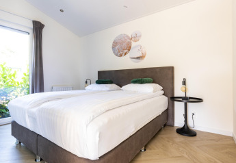 Dormitorio luminoso con dos camas individuales, decoración moderna y ventana grande en Molenvelden 7.