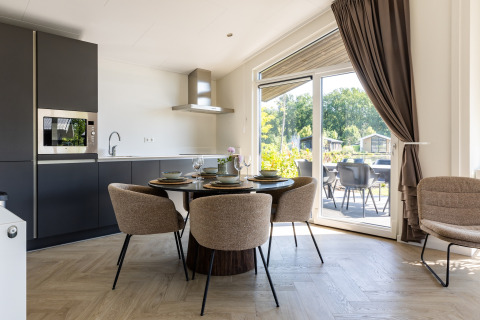 Modernes Chalet mit offener Küche und Essbereich, großen Fenstern, Terrasse im Holiday Park Molenvelden 7, Niederlande.